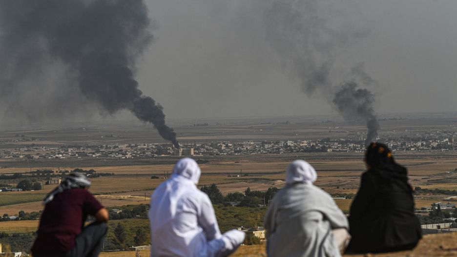 Atak Turcji na Syrię. Ludzie patrzą, jak dym unosi się z syryjskiego miasta Ras al-Ain, na zdjęciu wykonanym po tureckiej stronie granicy, w Ceylanpinar, 11 października br.