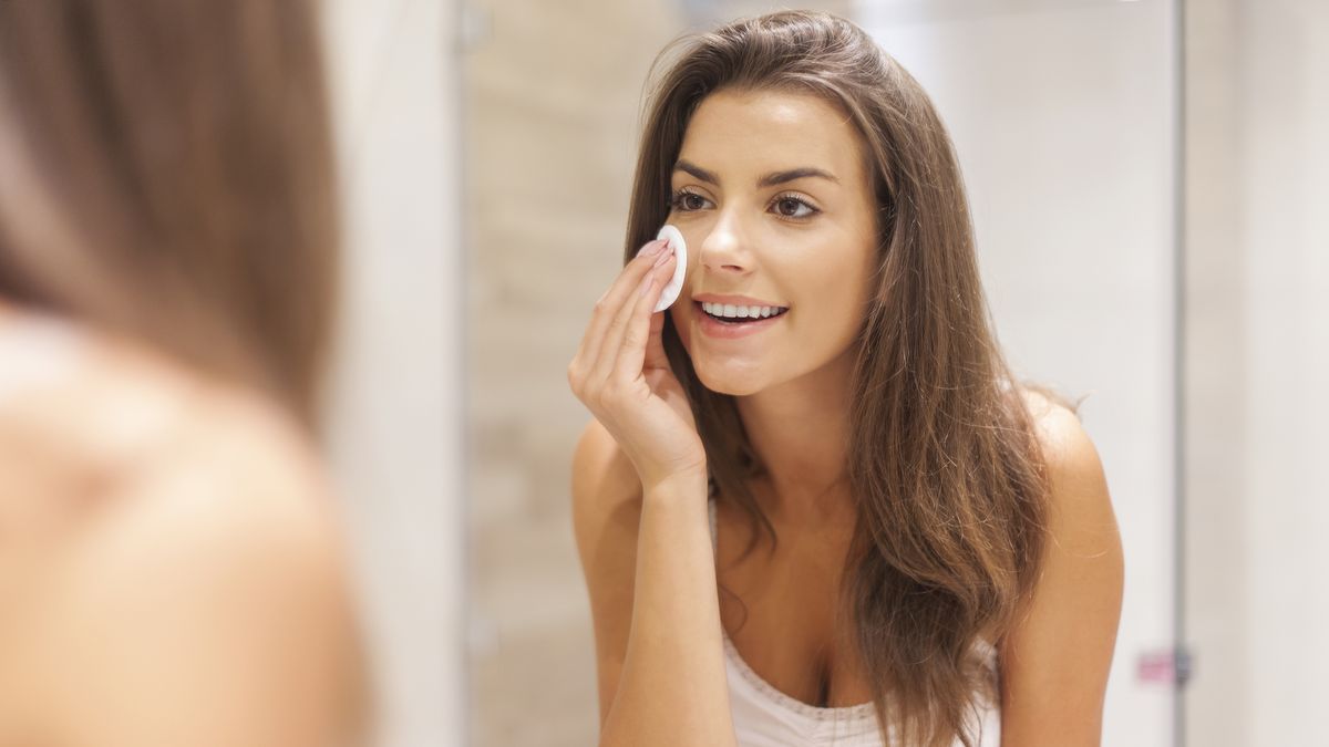 Beautiful brunette woman removing makeup from her face