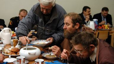 Bezdomni częstują się zupą podaną podczas uroczystego otwarcia jadłodajni