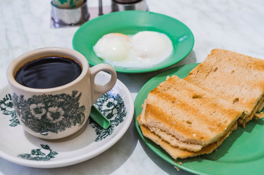 Singapore Breakfast called Kaya Toast, Coffee bread and Half-boiled eggs, Chinese coffee in vintage mug and bread toast with a local jam made from eggs, sugar and coconut milk, The fractal on the cup is generic print