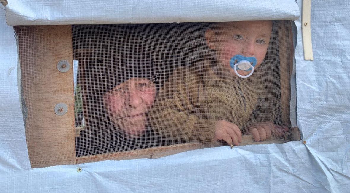 Kobieta z dzieckiem wygląda przez prowizoryczne okienko swojego prowizorycznego domu w obozie dla uchodźców w Arsalu 