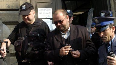 Paweł Huelle wychodzi z gmachu sądu eskortą policji