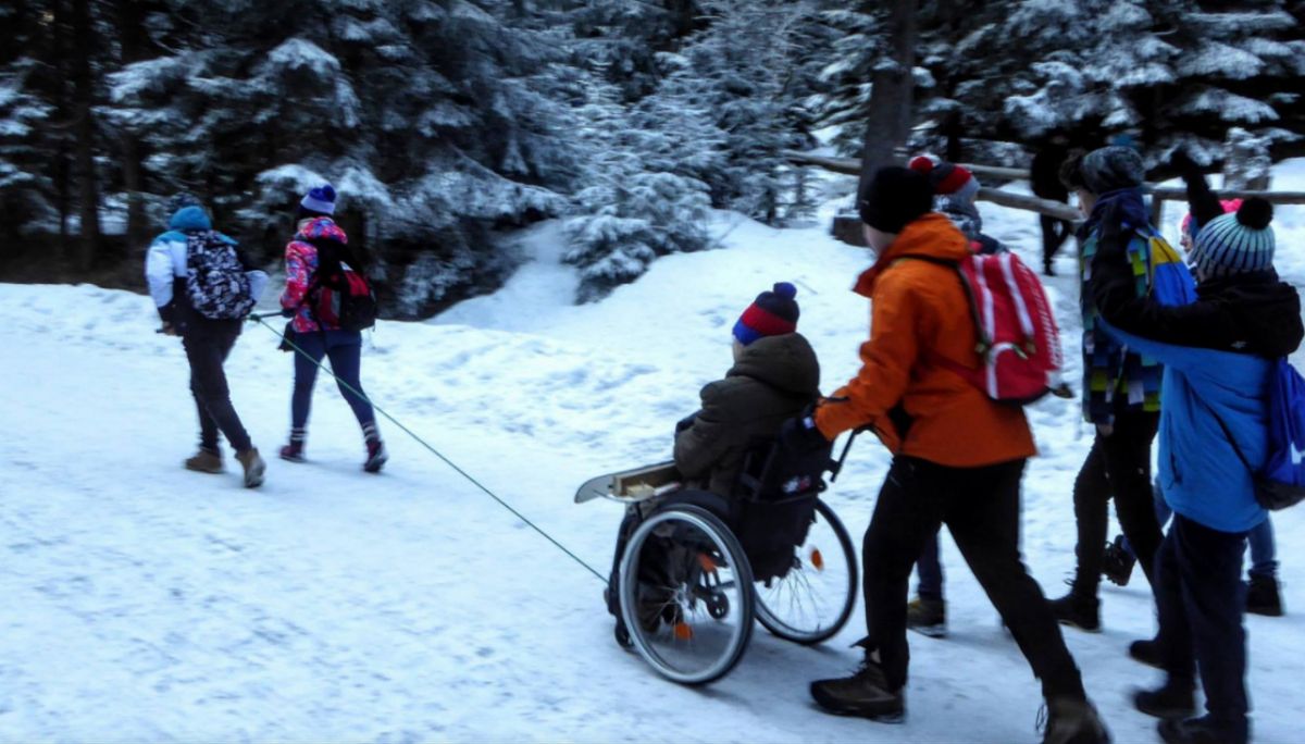 Grupka osób pomaga niepełnosprawnemu dostać się na Morskie Oko