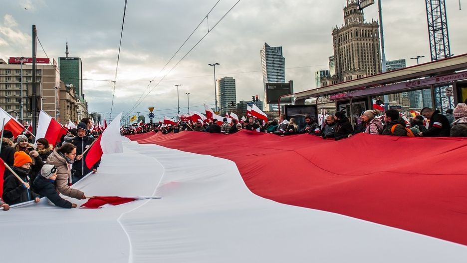Wielka flaga Polski niesiona przez ludzi w Marszu Niepodległości w Warszawie