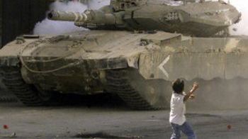 Palestyński chłopiec rzuca kamieniem w izraelski czołg