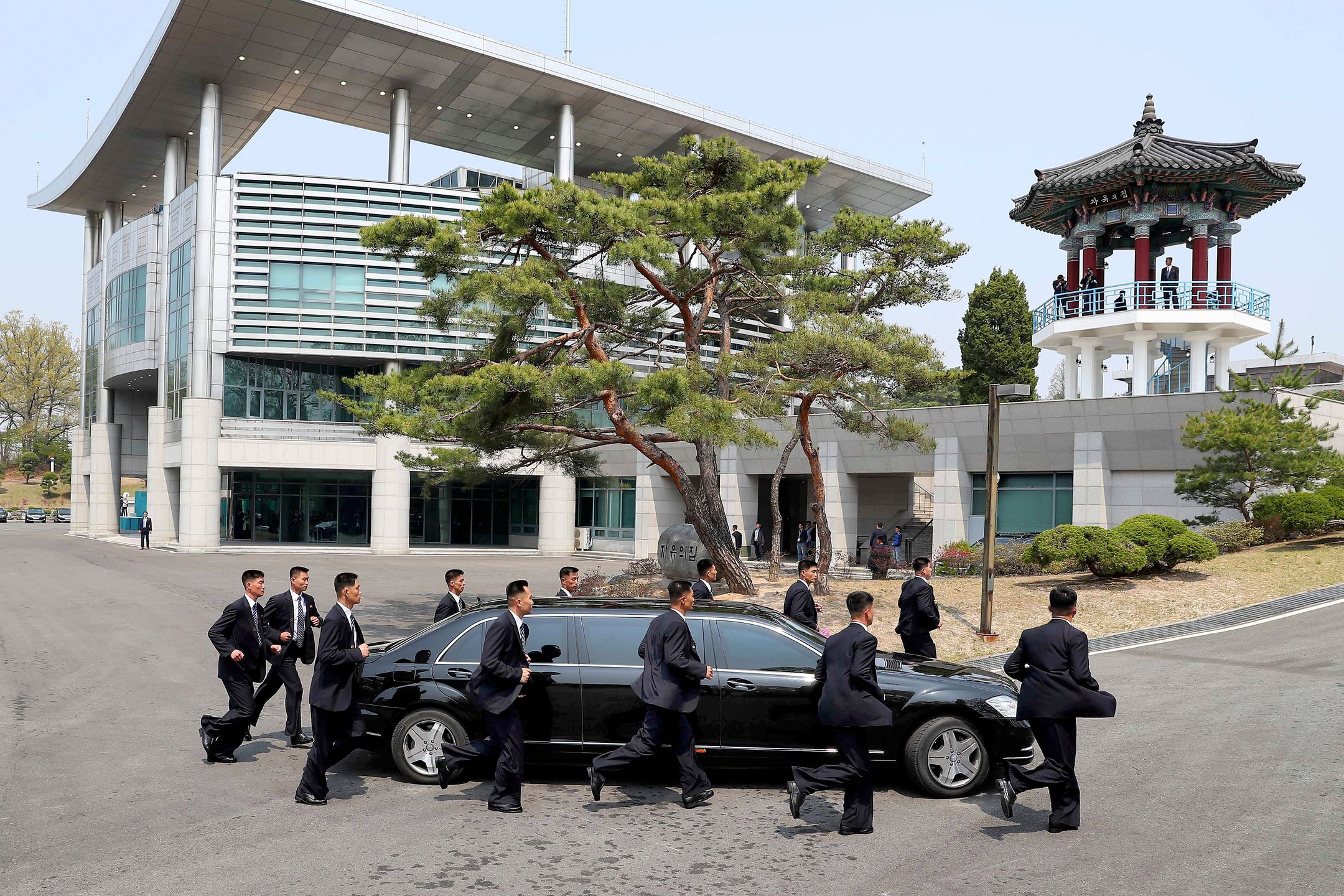 Security personnel run alongside a vehicle carrying North Korean leader Kim Jong Un at the truce village of Panmunjom inside the demilitarized zone separating the two Koreas, South Korea, April 27, 2018.   Korea Summit Press Pool/Pool via Reuters 