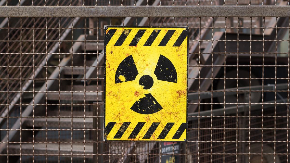 yellow radioactive warning sign on rusty fence 