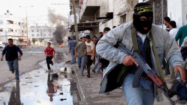 Palestyński bojownik ucieka z linii ognia podczas starć z izraelskimi żołnierzami w Gazie