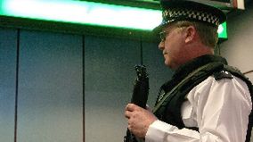 Uzbrojony policjant obserwuje odprawę pasażerów odlatujących do USA liniami BA lot 223 na lotnisku Heathrows.