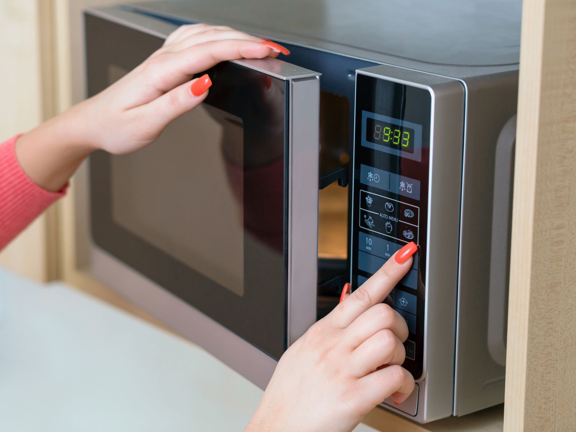 Detail of female hand while using the microwave 