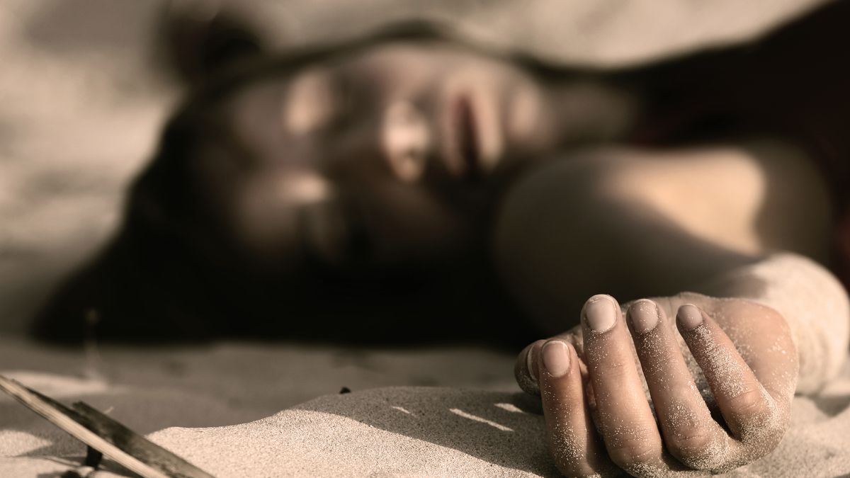 woman playing dead, lying in the sand