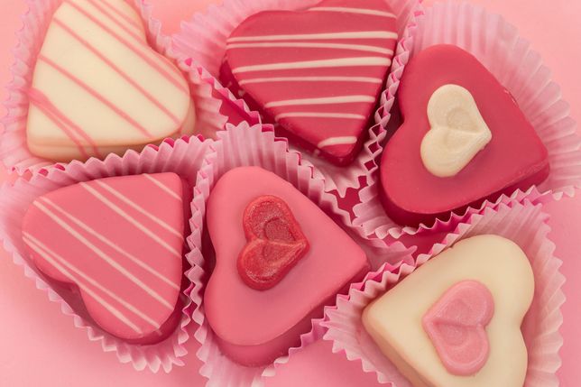 Pink heart shaped petit fours cakes seen from above on a pink background 