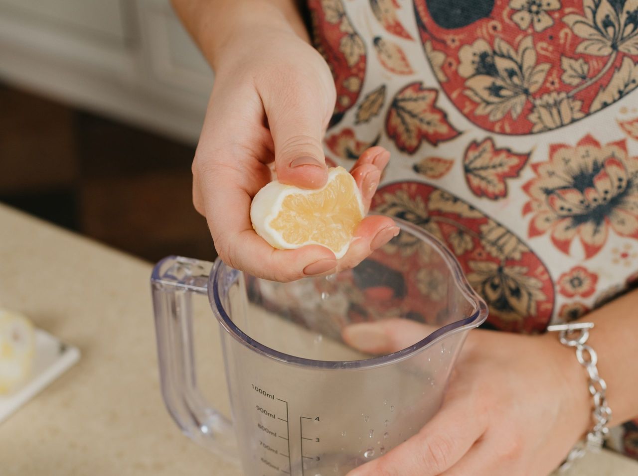 The hands of woman who is crushing lemon juice by the hand into the blender cup