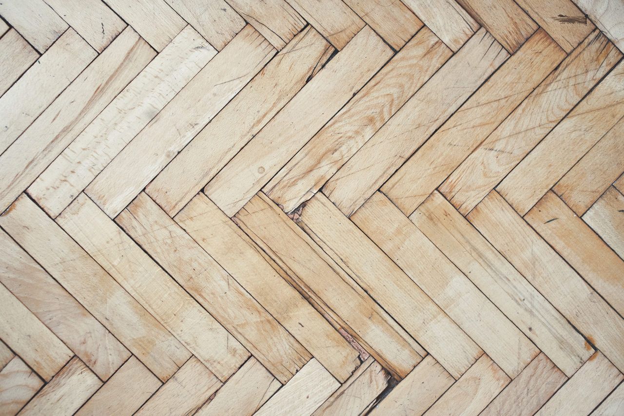 Top view on rich texture of old brushed and distressed wooden parquet floor made from many racks in herringbone pattern