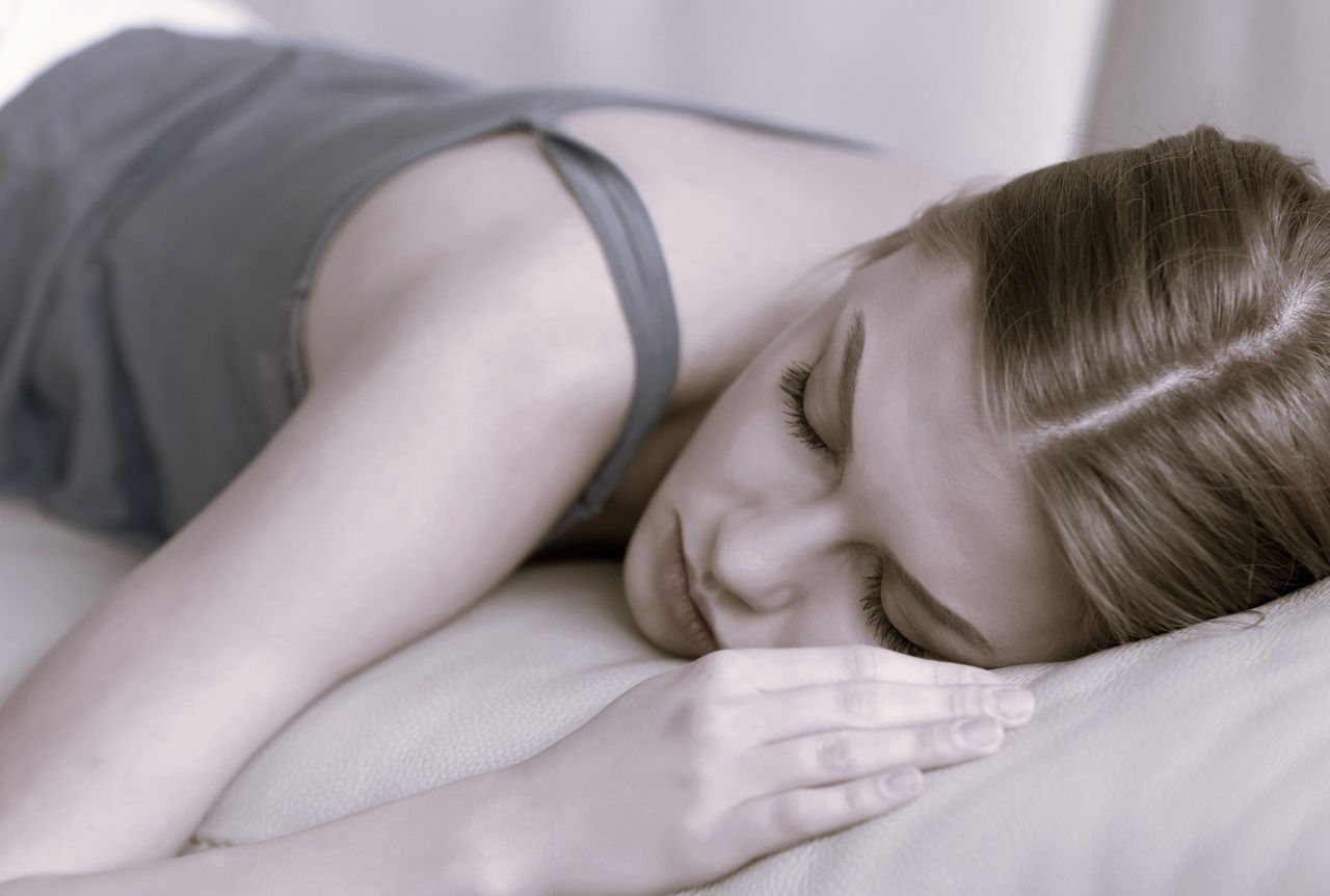 Young deprived sleeping woman lying asleep on sofa, close up