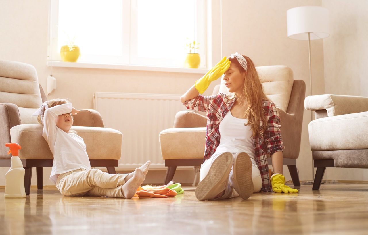 A mother and a daughter feeling exhausted after cleaning home together