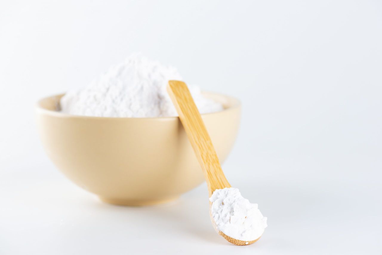 Tapioca starch or flour powder. White powdered tapioca starch in a wooden spoon and bowl, cassava root powder.