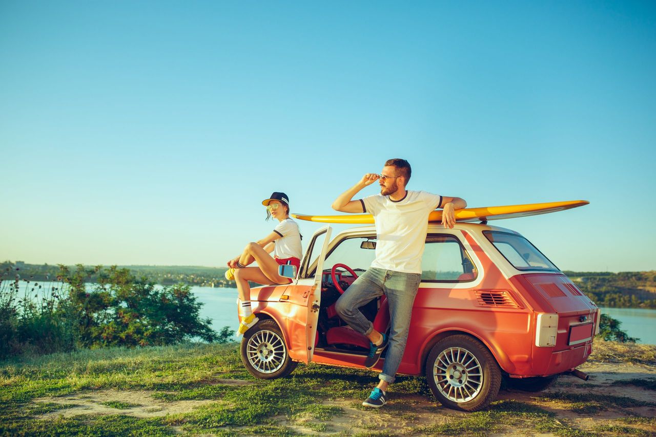 Couple sitting and resting on the beach on a summer day near river. Love, happy family, vacation, travel, summer concept. Caucasian man and woman