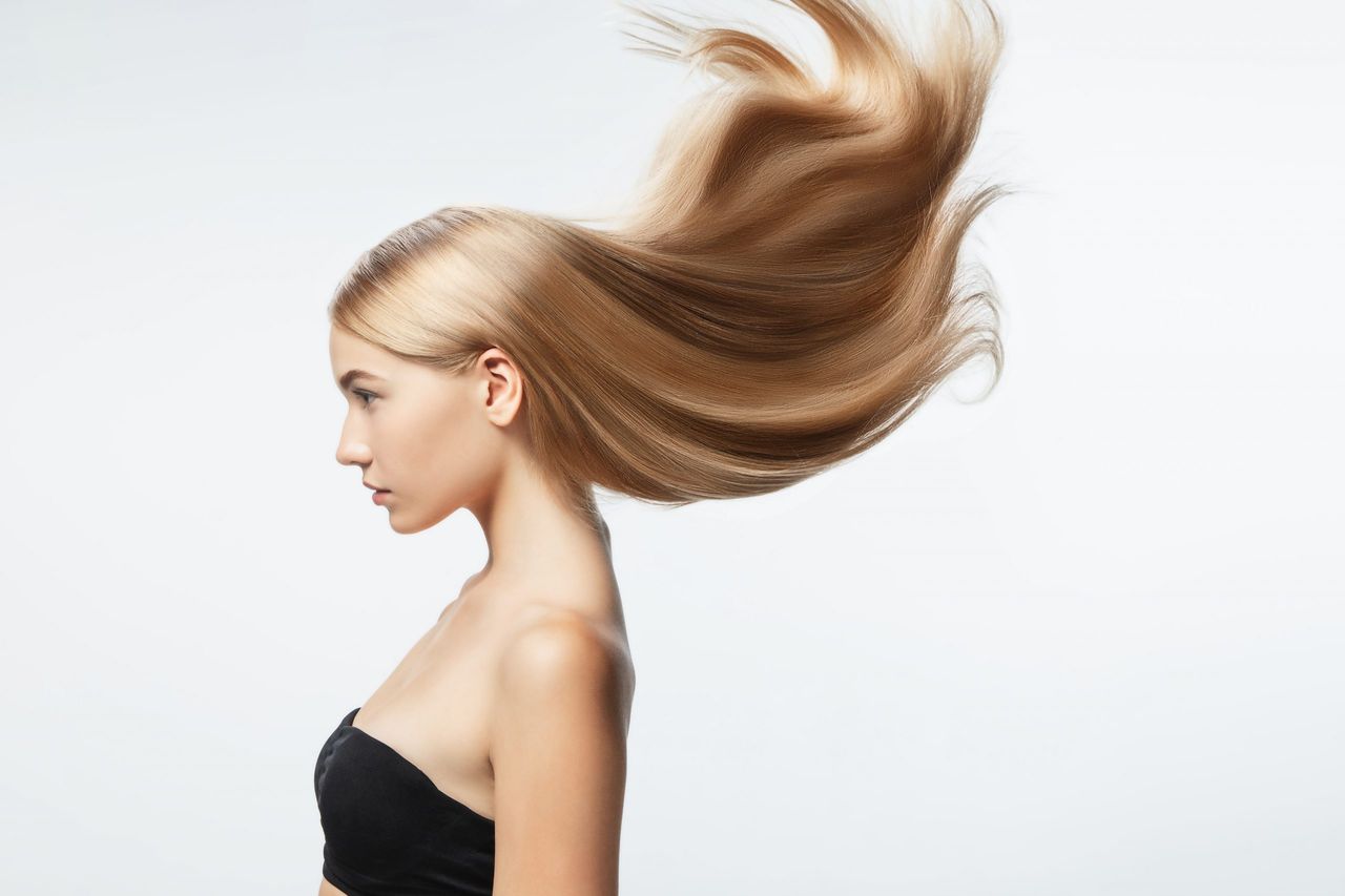 Beautiful model with long smooth, flying blonde hair isolated on white studio background. Young caucasian model with well-kept skin and hair blowing on air. Concept of salon care, beauty, fashion.