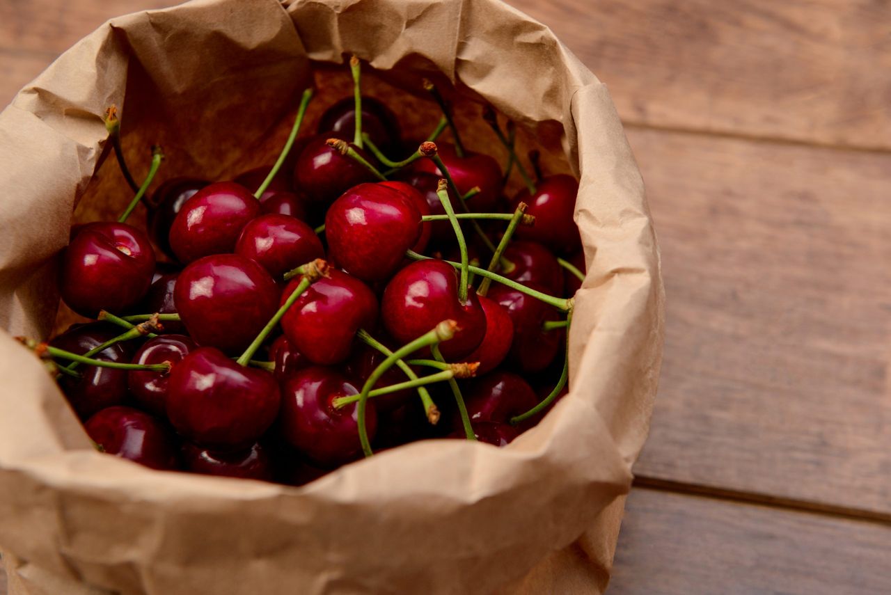 Cherry in package on wooden table. Macro.