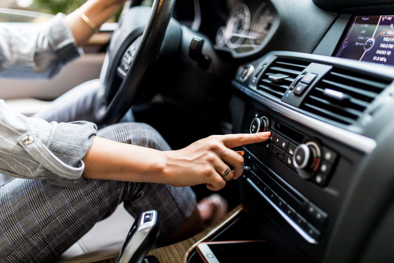 Car dashboard. Radio closeup. Woman sets up radio