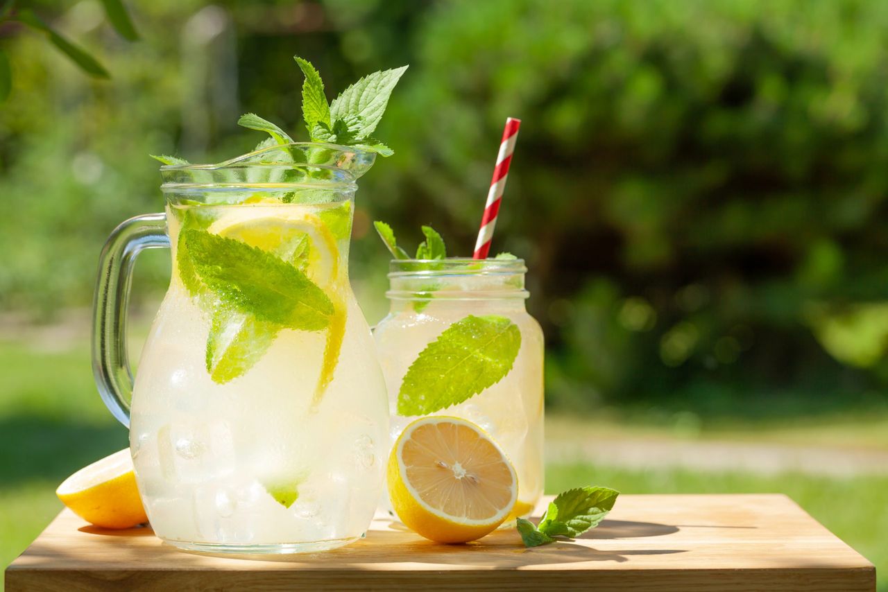 Fresh homemade lemonade with lemon and mint. Outdoor garden table on sunny day