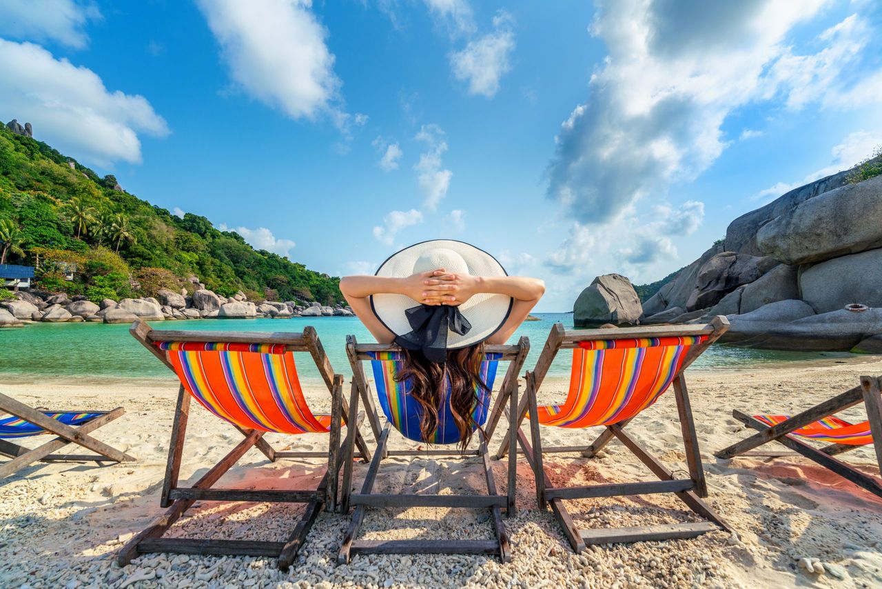 Woman with hat sitting on chairs beach in beautiful tropical beach. Woman relaxing on a tropical beach at Koh Nangyuan island.