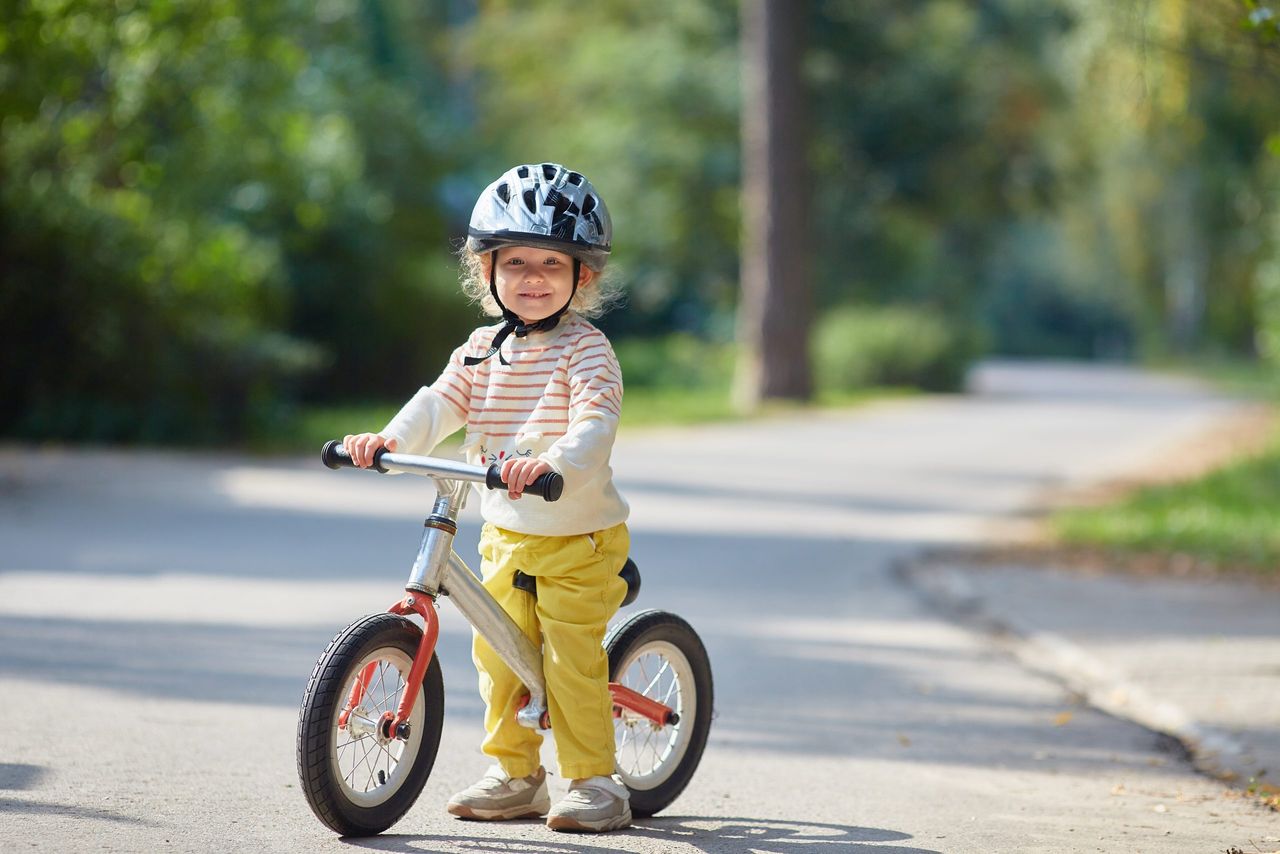 satisfied child on a balance bike in a helmet. On a sunny summer day. Copy space.