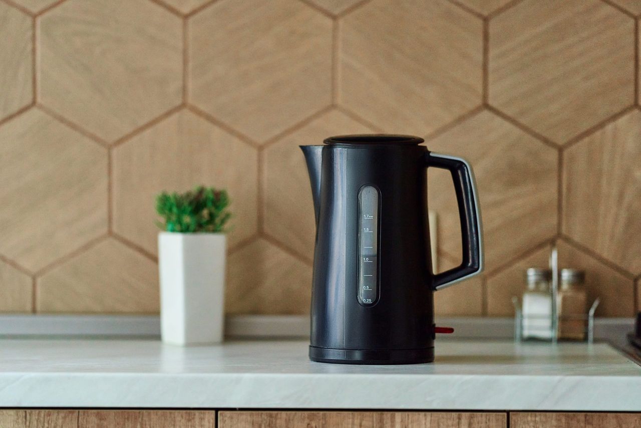 Black plastic electric kettle on the white countertop. Household kitchen appliances for makes hot drinks