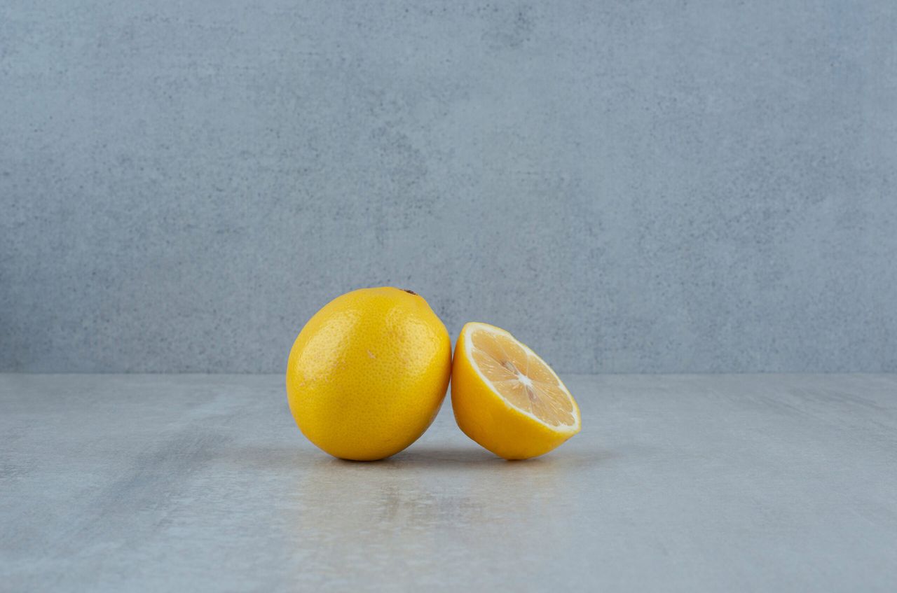 Whole and half cut lemons on blue background. High quality photo