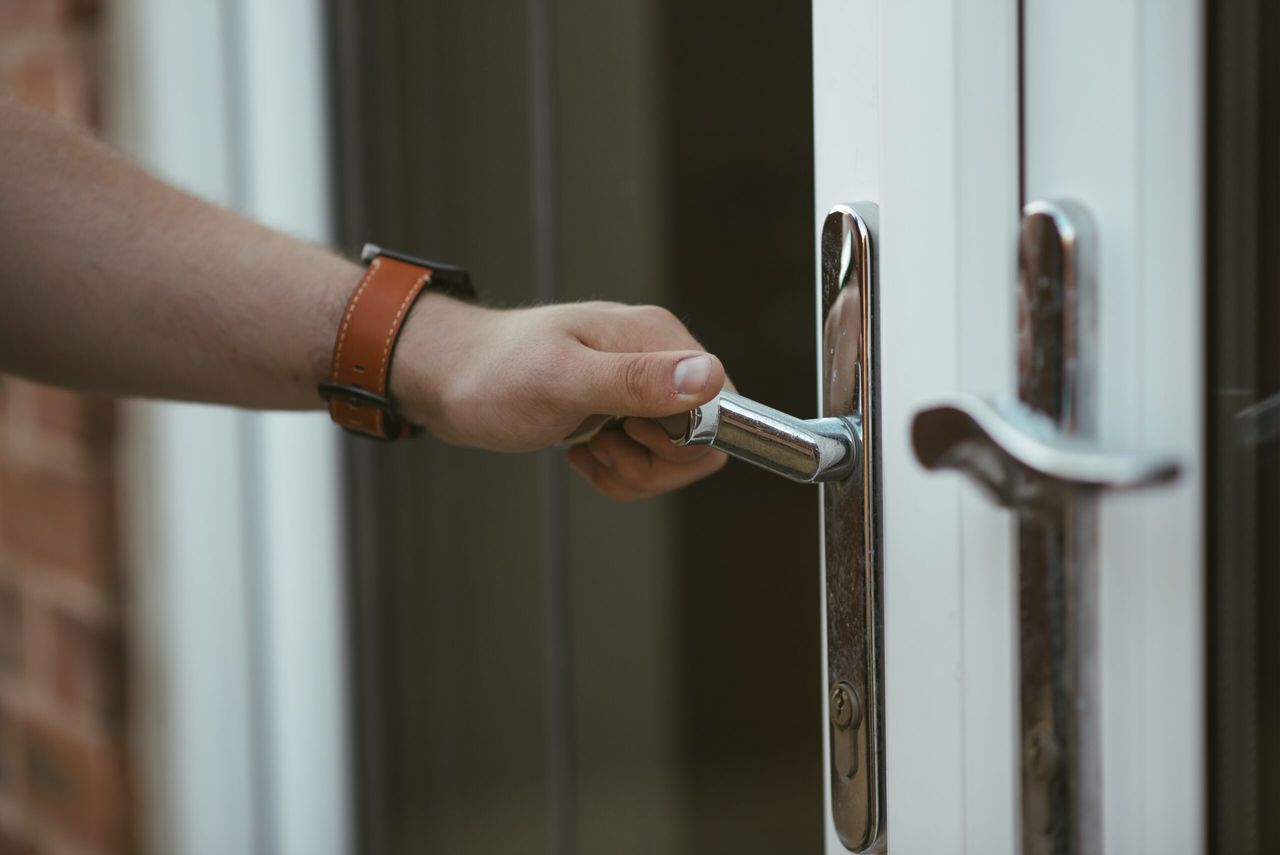 A closeup shot of a person holding a door knob and opening the door
