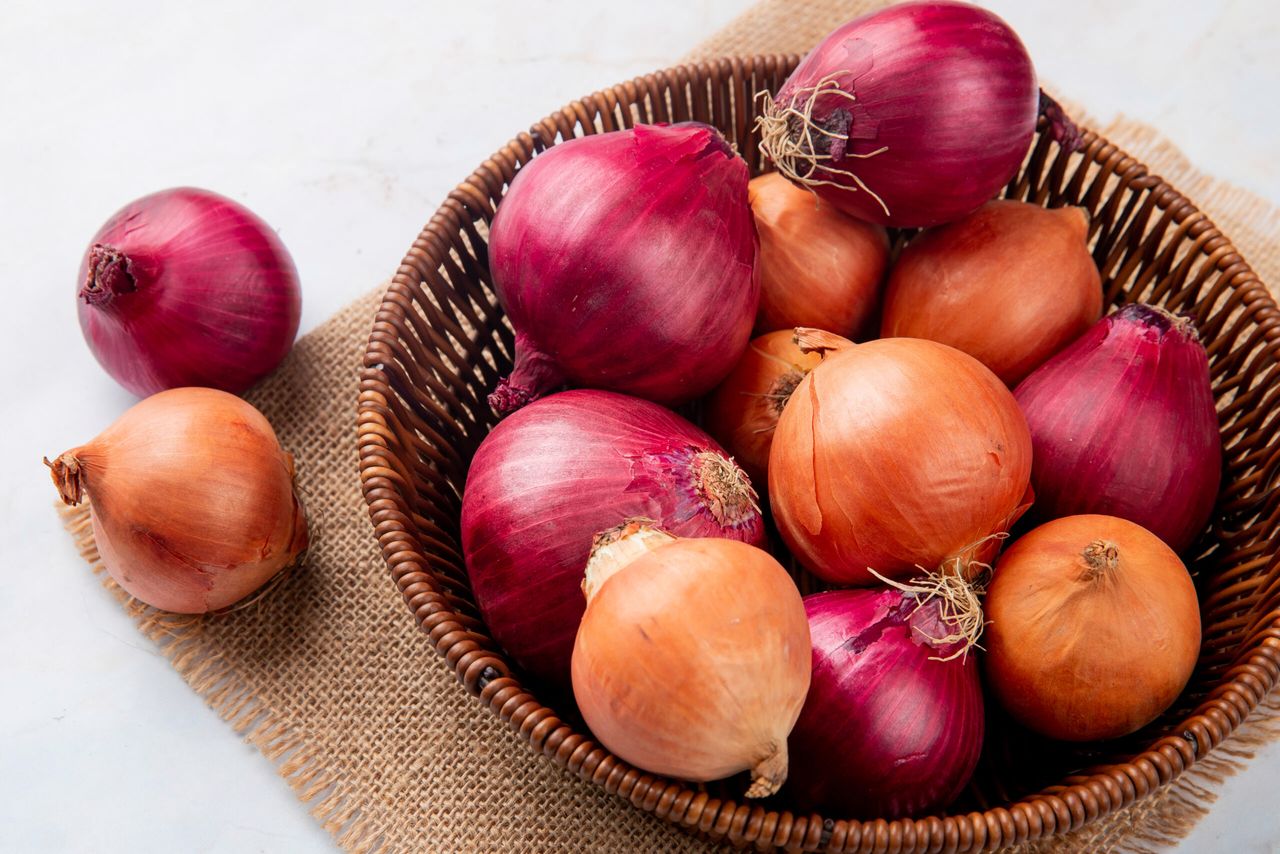 close-up view of basket of onions on sackloth on white background