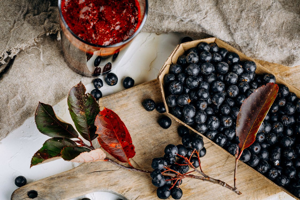 Fresh aronia berries and berry juice in a glass