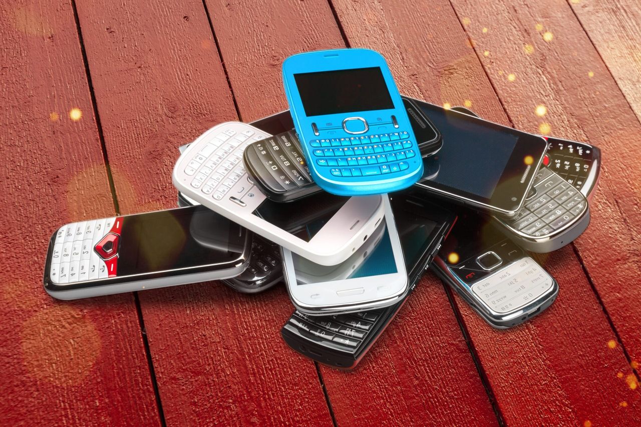 Pile of old smartphones on wooden background