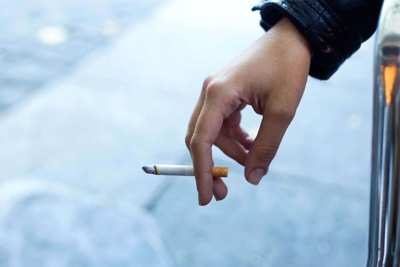 Close up of womans hand with cigarette in the street.