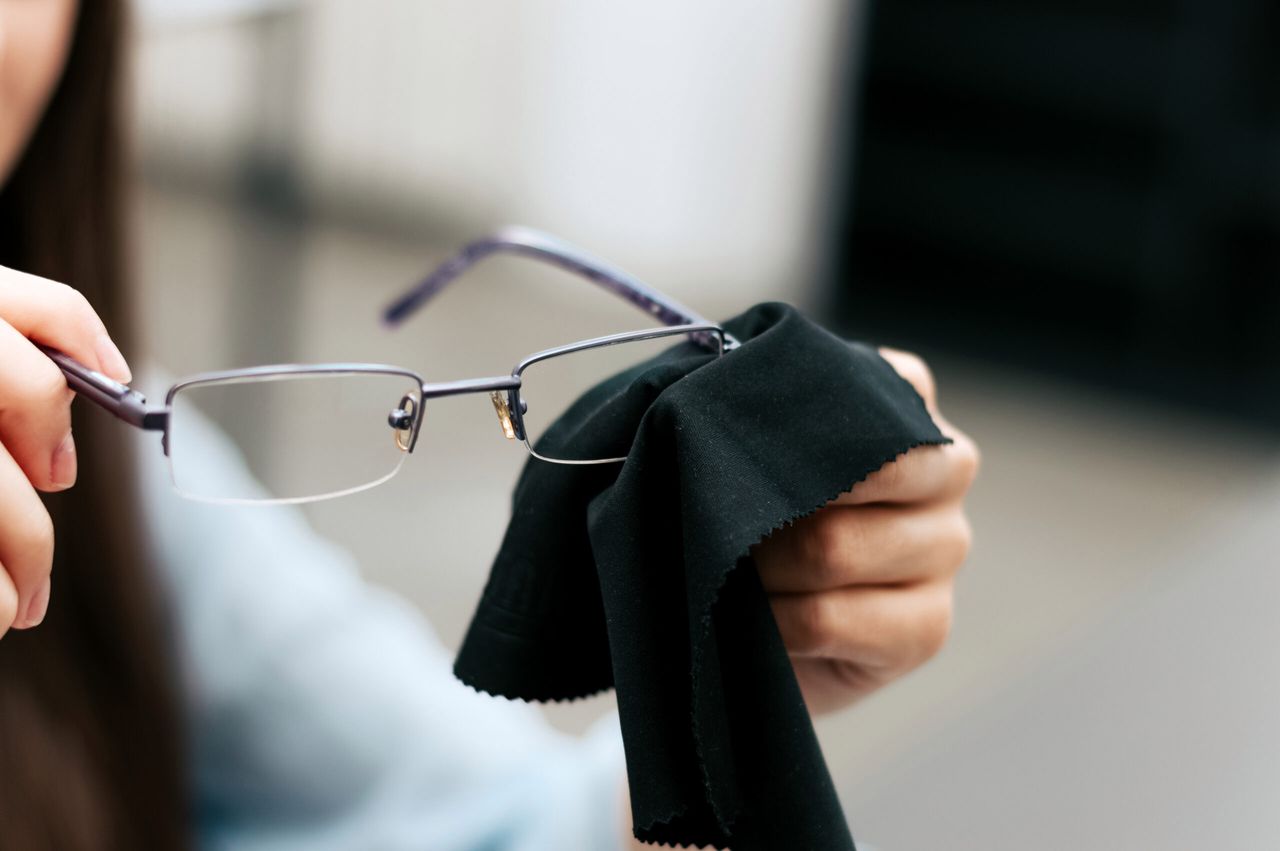 Woman cleaning her glasses with black cloth.