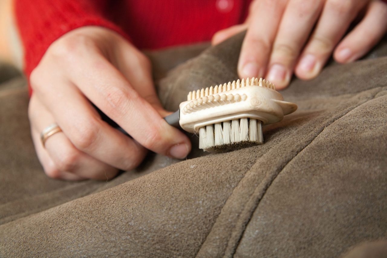 Closeup of Woman cleaning a sheepskin with whisk broom