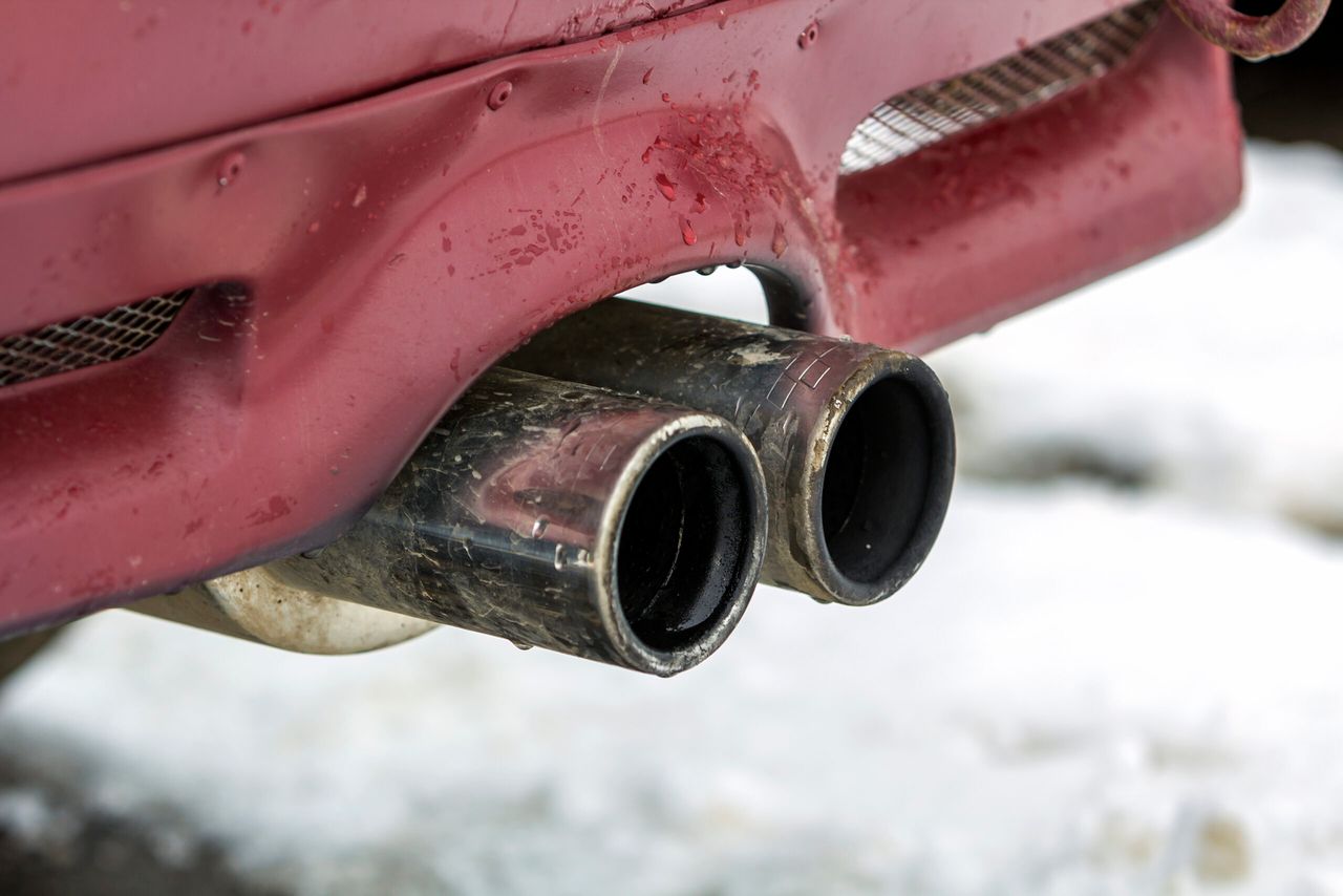 Close up image of a car dual exhaust pipe. Emission of poisonous carbon monoxide gas in atmosphere, environment pollution concept.