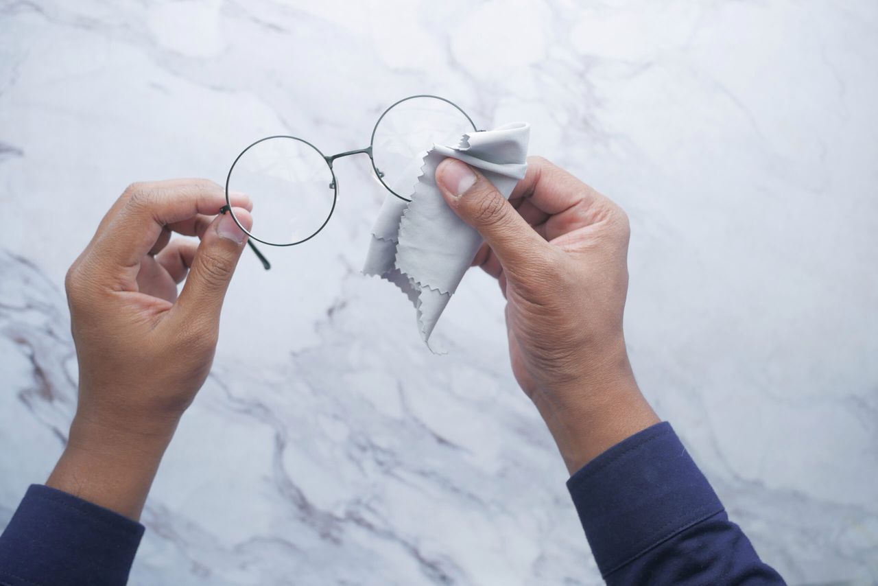 cleaning eyeglass with tissue close up .