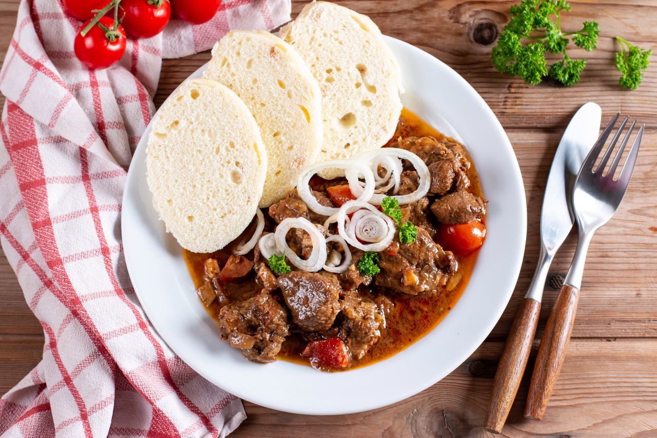 Beef goulash and dumplings (knedliky) on wooden table from Czech Republic