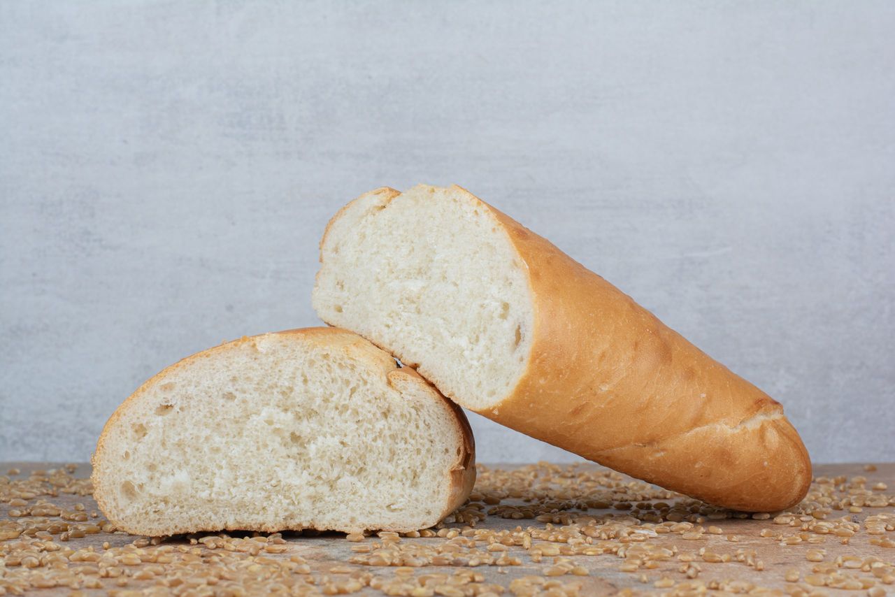 Half cut wheat bread with barley on marble table. High quality photo