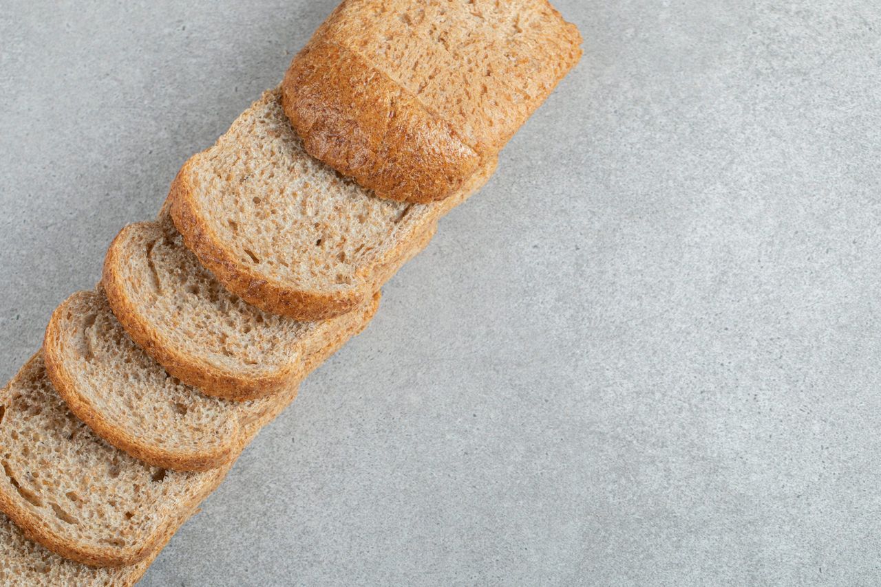 A line of slices of brown bread on a gray background . High quality photo