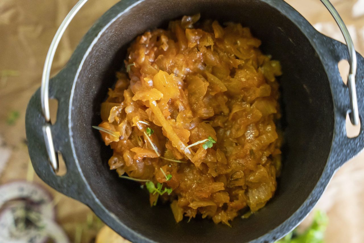 delicious stewed cabbage in a cast-iron pot served in a restaurant with meat. culinary delights. you 'll lick your fingers