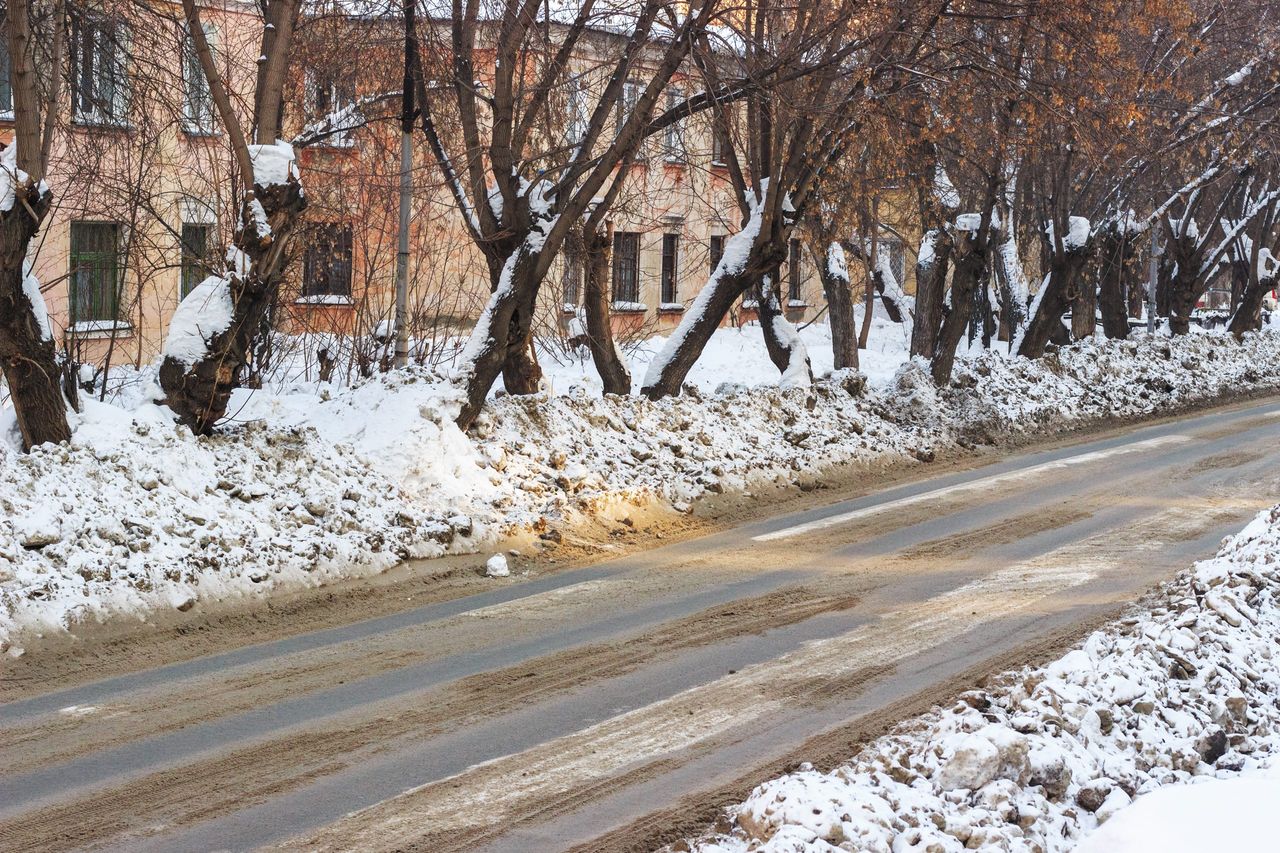 Dirty snow on the streets of the city in Siberia. Sand and reagents against icy condition.