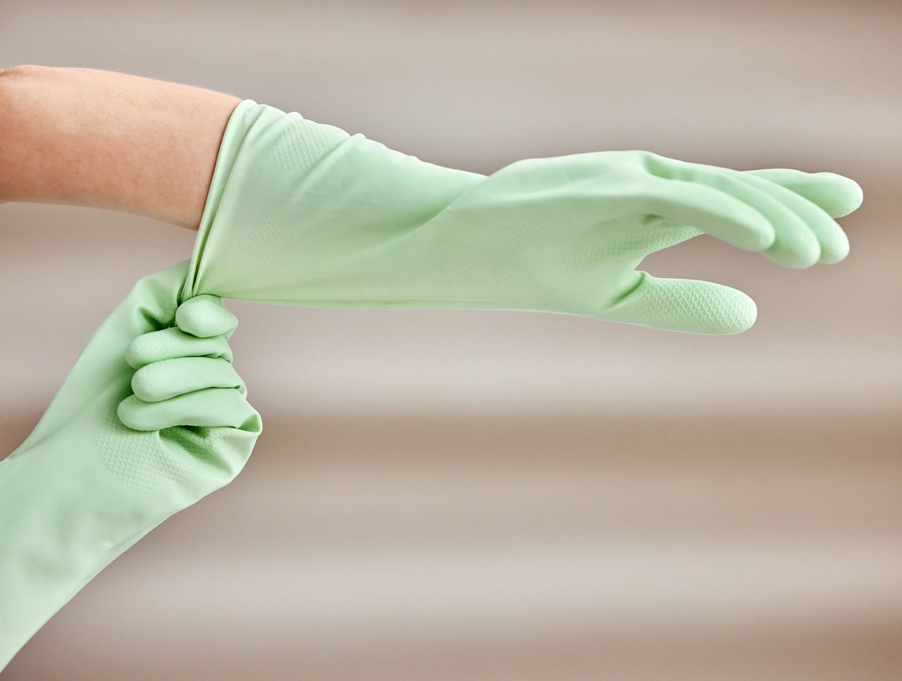 Shot of an unrecognizable person putting on gloves at home.