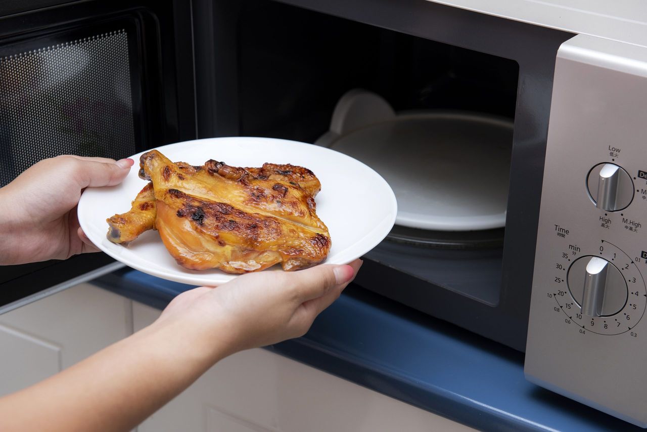 Women hand holding food in a microwave oven