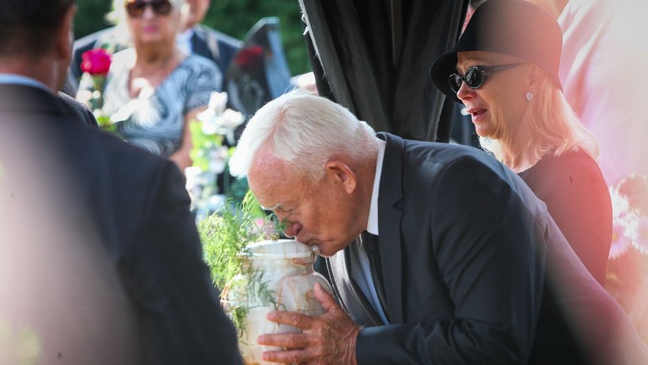 Leszek Miller całuje urnę z prochami syna