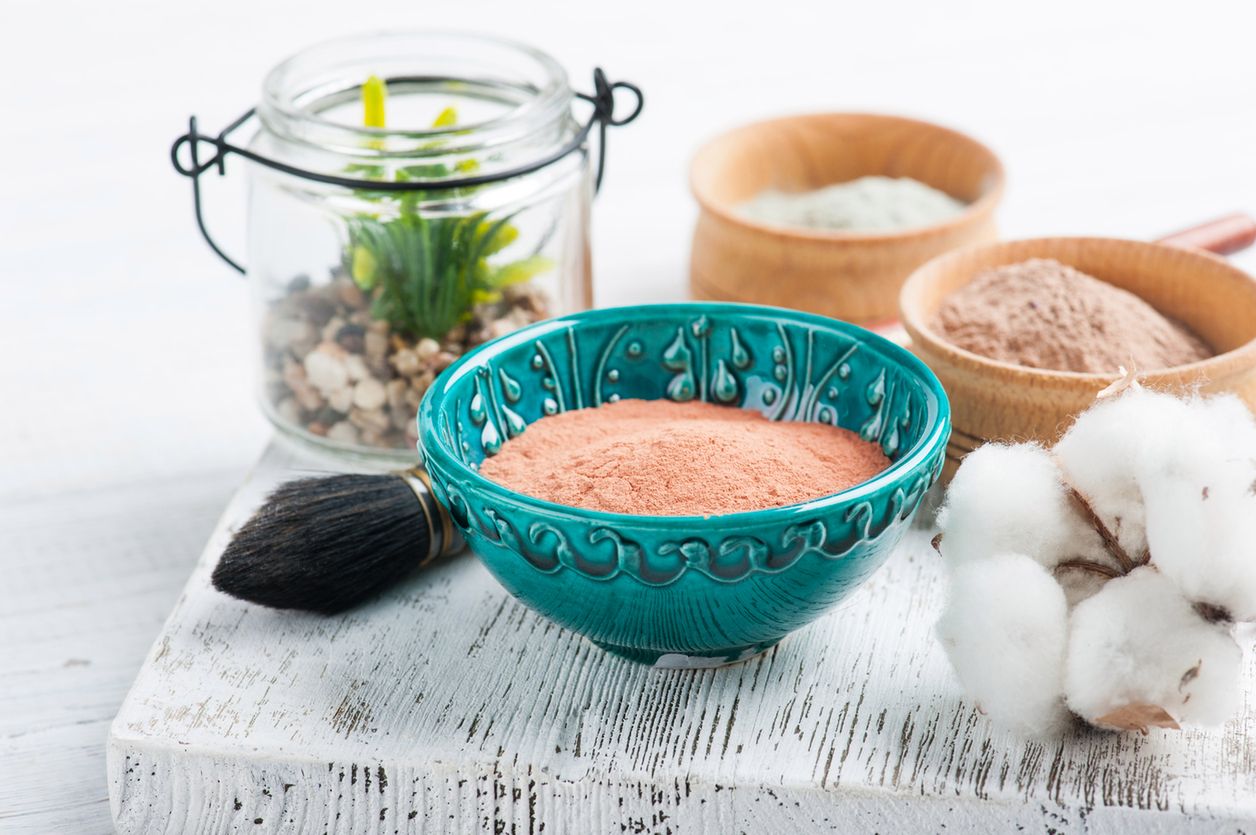 Red and blue cosmetic moroccan clay powder, spa composition with brush on white background 