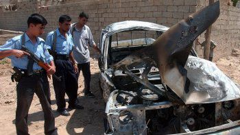 Iraccy policjanci oglądają wrak auta zniszczonego w wybuchu