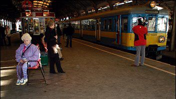 Wiązanki kwiatów i znicze na tablicy wmurowanej w chodnik peronu